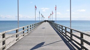 En träbrygga som sträcker sig ut i havet, med flera flaggor på stång.