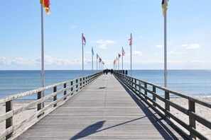 A wooden pier extending into the sea with multiple flags on poles. - Holiday apartment with 1 bedroom (Großenbrode)