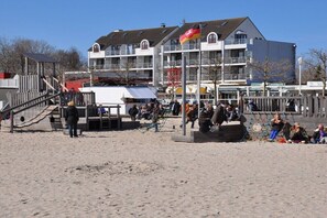 A beachside building with multiple balconies, a sandy foreground, and a clear sky. - Holiday apartment with 1 bedroom (Großenbrode)