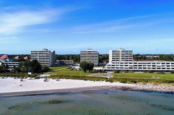 A coastal hotel with multiple buildings, a sandy beach, and a clear sky. - Holiday apartment with 1 bedroom (Großenbrode)