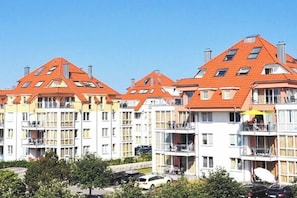 A multi-story residential building with a red-tiled roof, balconies, and a clear sky. - Holiday apartment with 2 bedrooms (Großenbrode)
