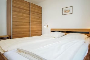 A bedroom with a wooden wardrobe, a bedside lamp, and a framed picture on the wall. - Holiday apartment with 2 bedrooms (Großenbrode)