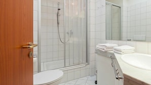 Une salle de bain comprenant des toilettes, un espace douche et un lavabo avec un miroir.