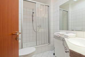 Un baño con inodoro, cabina de ducha y lavabo con espejo.