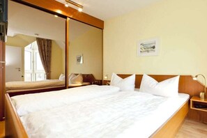 Habitación de hotel con una cama grande, una mesita de noche, un espejo y un cuadro en la pared.