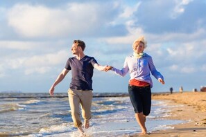 Dos personas caminando por la playa tomadas de la mano.