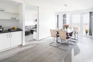 Une cuisine moderne avec des meubles blancs et un coin repas comprenant une table et des chaises.