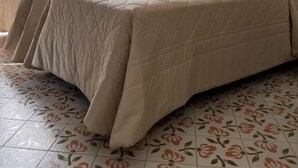 Quarto de hotel com duas camas, varanda e vista para montanhas, e piso com padrão floral.