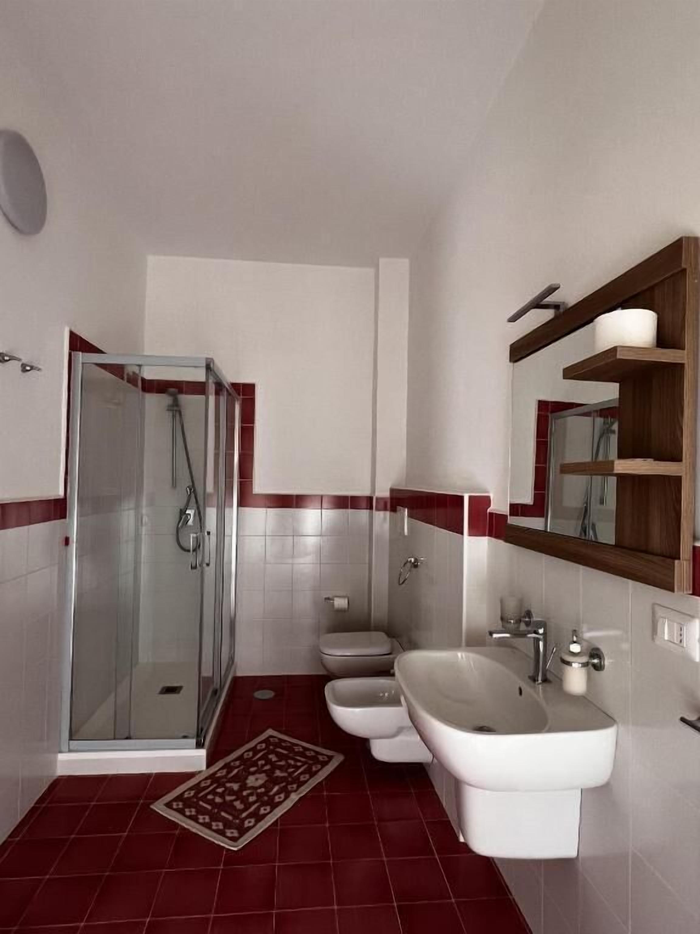 A bathroom with a glass shower enclosure, a toilet, a bidet, and a sink.