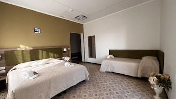 A hotel room with two beds, a large mirror, and a vase with flowers.