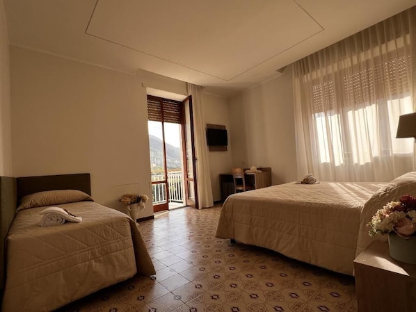 A hotel room with two beds, a television, and a balcony. - Oasi Cuore (Castellammare di Stabia)