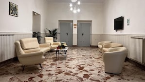 A lobby with seating, a chandelier, and a television.
