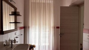 Casa de banho com lavatório, espelho e porta para outro quarto.
