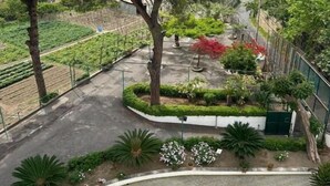 A courtyard with a round table and chairs, surrounded by trees and a garden.