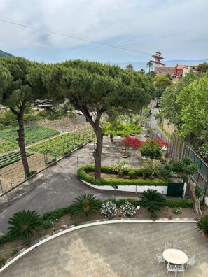 Un patio con una mesa redonda y sillas, rodeado de árboles y un jardín.