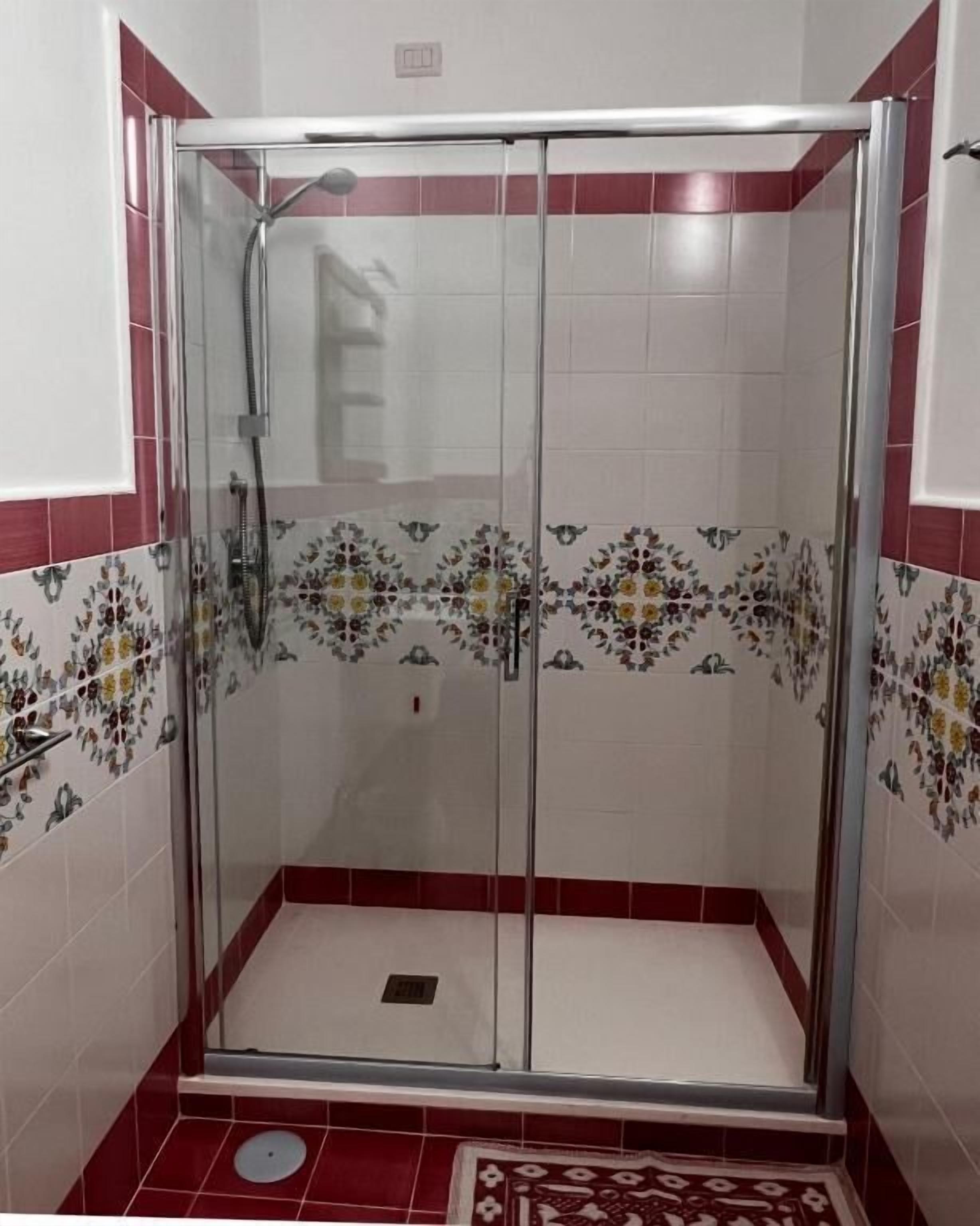 Cabina de ducha con paredes de vidrio, cabezal de ducha y panel de control.