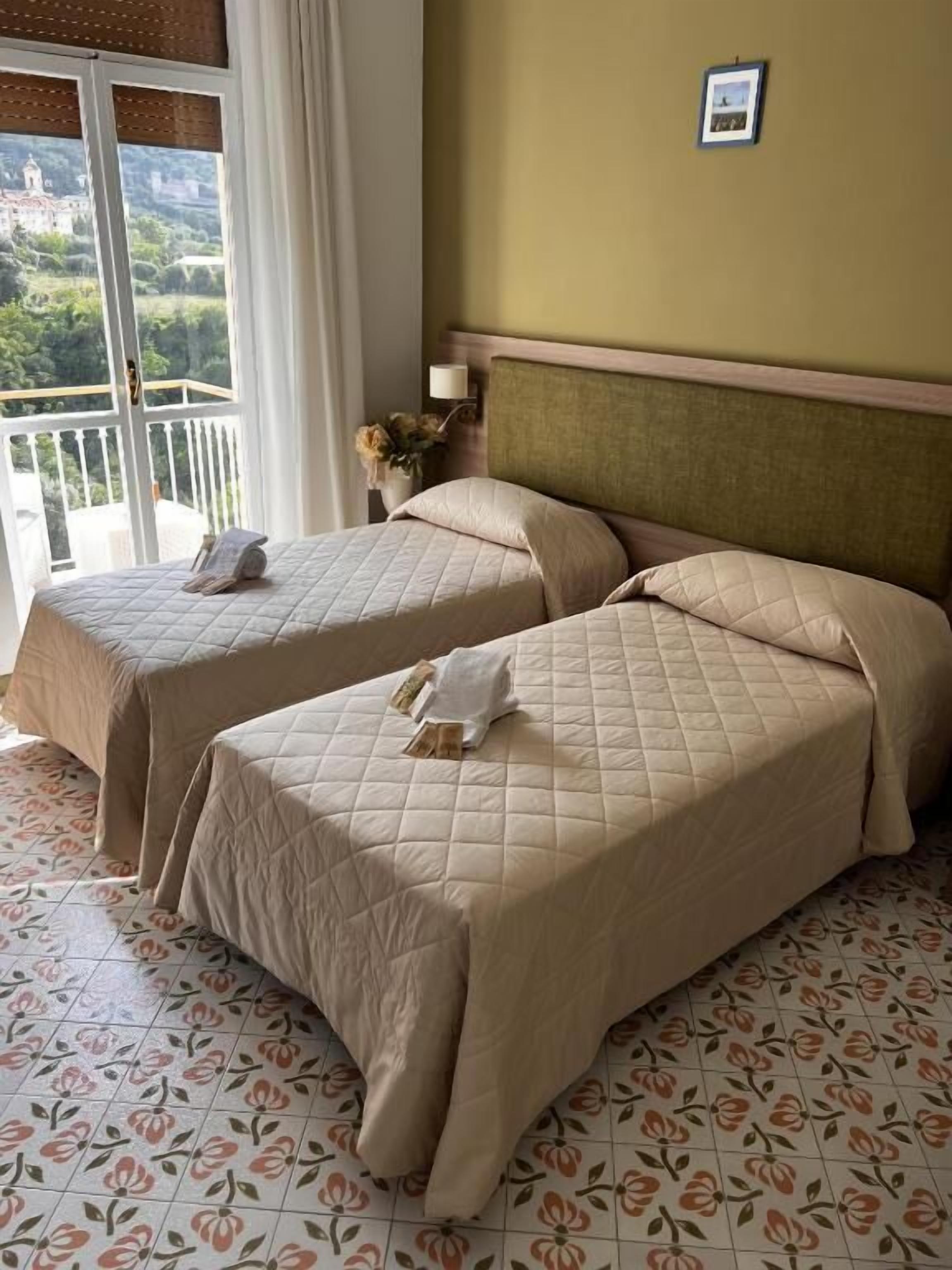 Een hotelkamer met twee bedden, een balkon en uitzicht op het landschap.