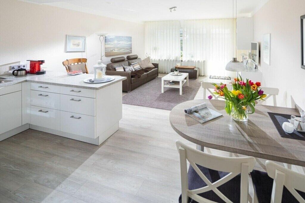 A modern living room with a sofa, coffee table, and a dining area with chairs and a table.