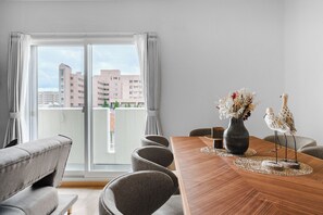 A modern dining area with a wooden table, grey chairs, a vase with flowers, and a decorative bird sculpture. - E-US NAEBO STATION 408 (Sapporo)