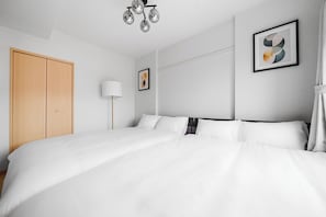 Habitación de hotel con una cama grande, un armario de madera, una lámpara de pie y un cuadro abstracto en la pared.