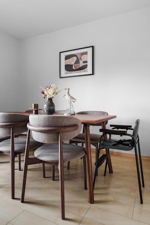 Un comedor con mesas y sillas redondas, un florero con flores y un cuadro en la pared.