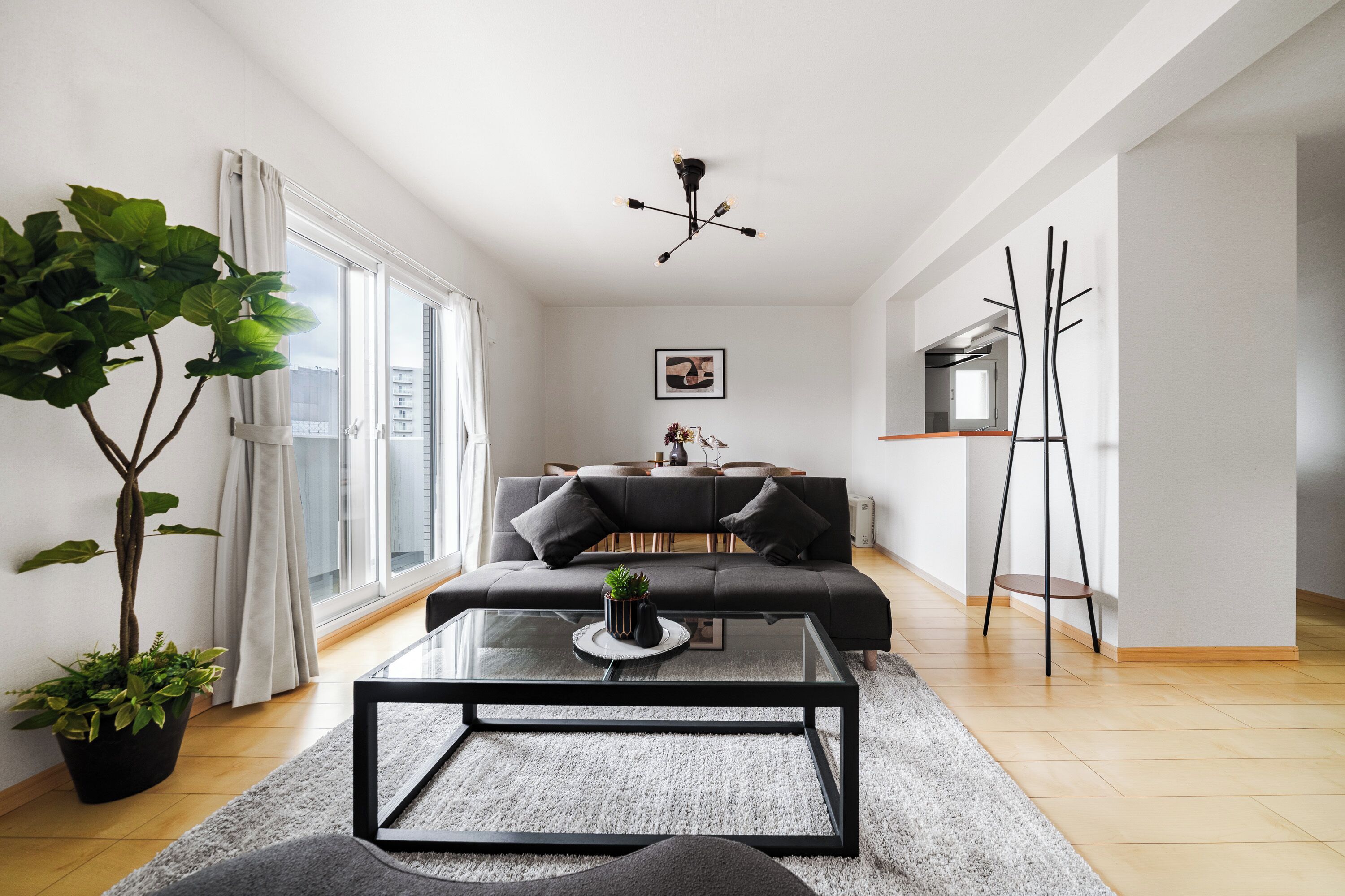 Ein modernes Wohnzimmer mit einer Couch, einem Couchtisch und einem Essbereich im Hintergrund.