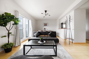 Una sala moderna con un sofá, una mesa de centro y un área de comedor al fondo.