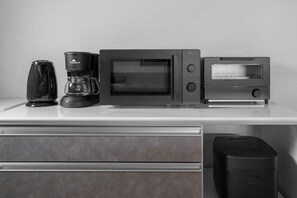 A kitchenette with a coffee maker, microwave, and toaster on a white countertop. - E-US NAEBO STATION 408 (Sapporo)