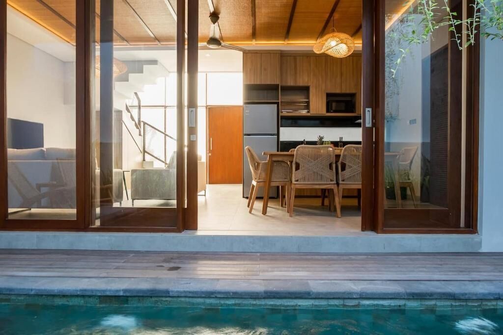 Un interior moderno con comedor, cocina y piscina.