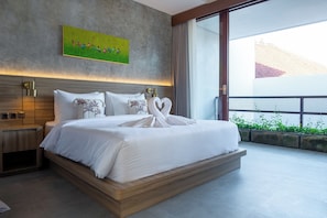 A modern hotel room with a large bed, a green artwork on the wall, and a view of greenery outside. - Solaris Canggu Villa by Tasvan (Badung)