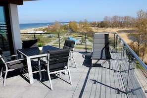 A balcony with outdoor furniture, a view of the sea, and a landscaped area. - Holiday apartment with 2 bedrooms (Heiligenhafen)
