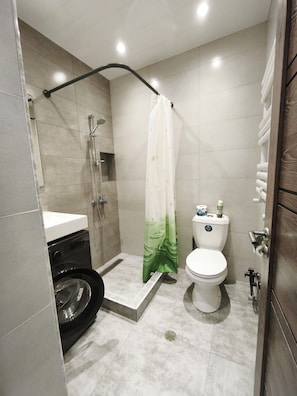 Un bagno compatto con doccia, WC e lavatrice.