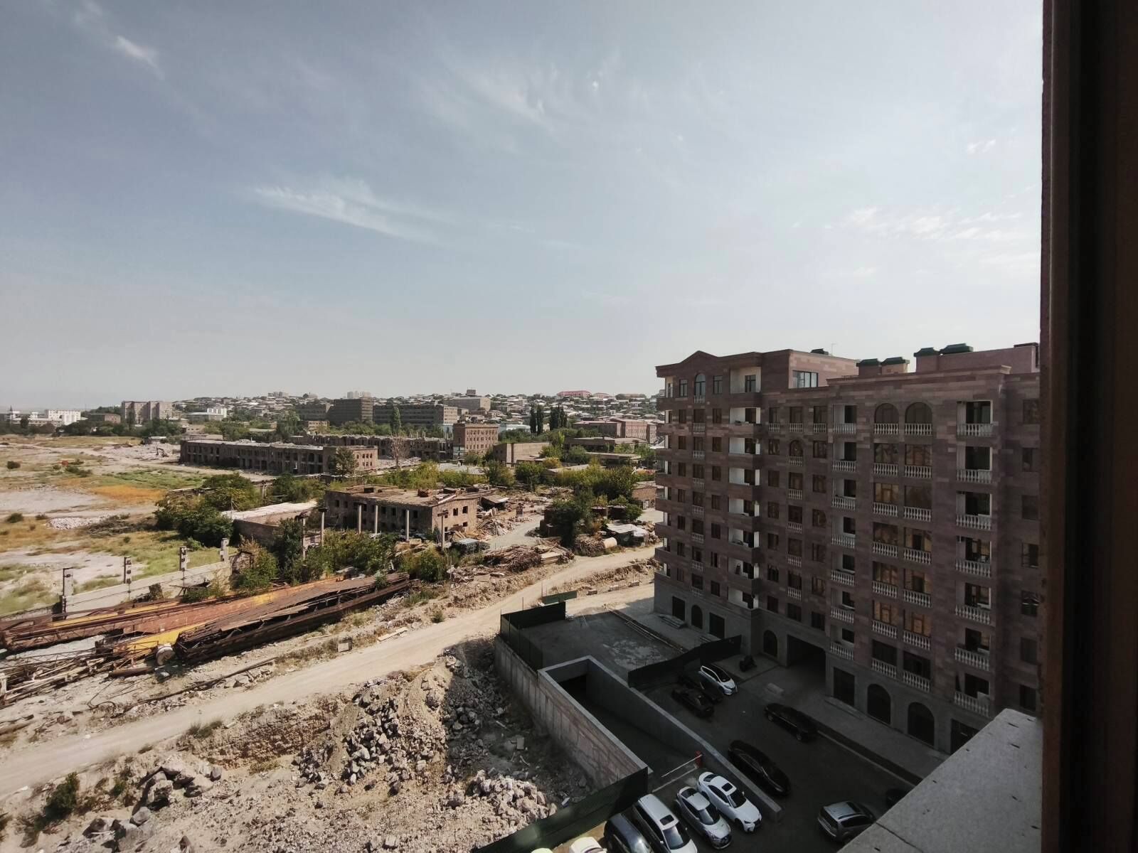 Vista de un paisaje urbano, con un edificio grande al frente y una vía de tren al fondo.