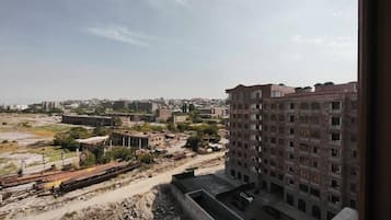 Vista de un paisaje urbano, con un edificio grande al frente y una vía de tren al fondo.