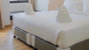 A hotel room with a bed, curtains, a window, and a view of buildings outside. - PT Residence Chonburi (Mueang Chon Buri)