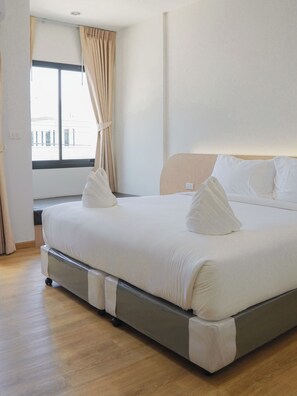 Hotellihuone, jossa on sänky, verhot, ikkuna ja näkymä ulkopuolella oleviin rakennuksiin.