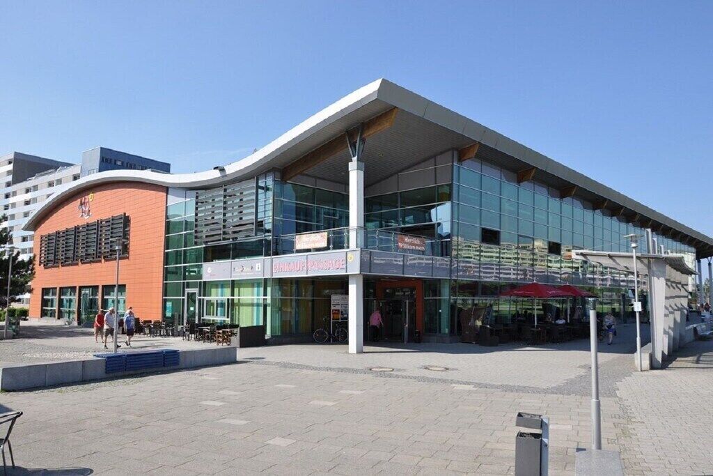 A modern building with a glass facade, a prominent entrance, and outdoor seating.