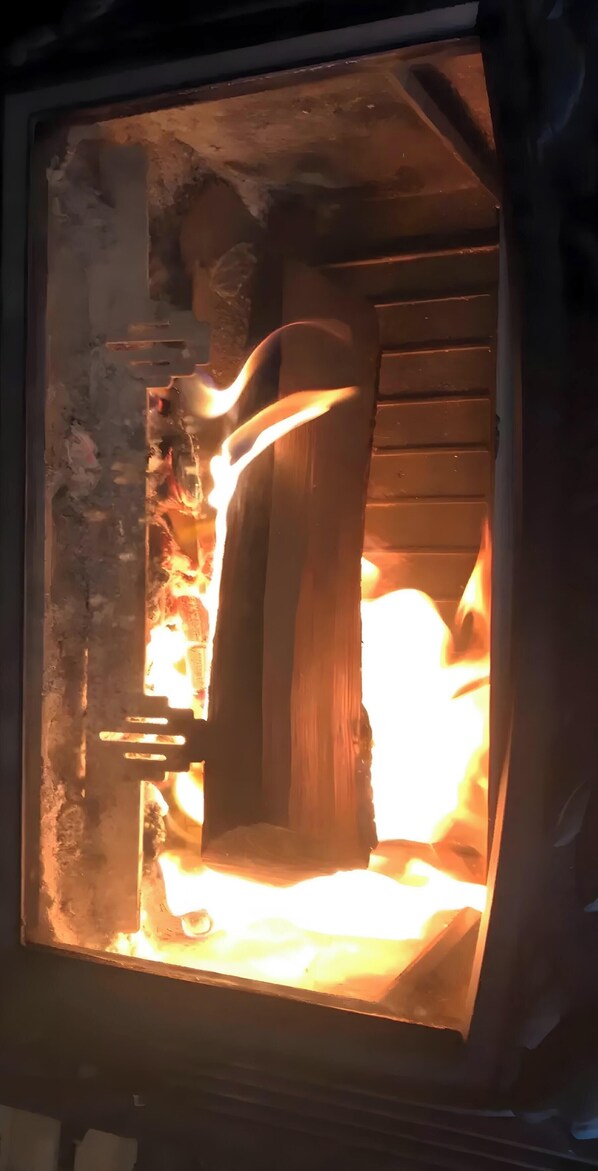 A fireplace with a log burning inside.