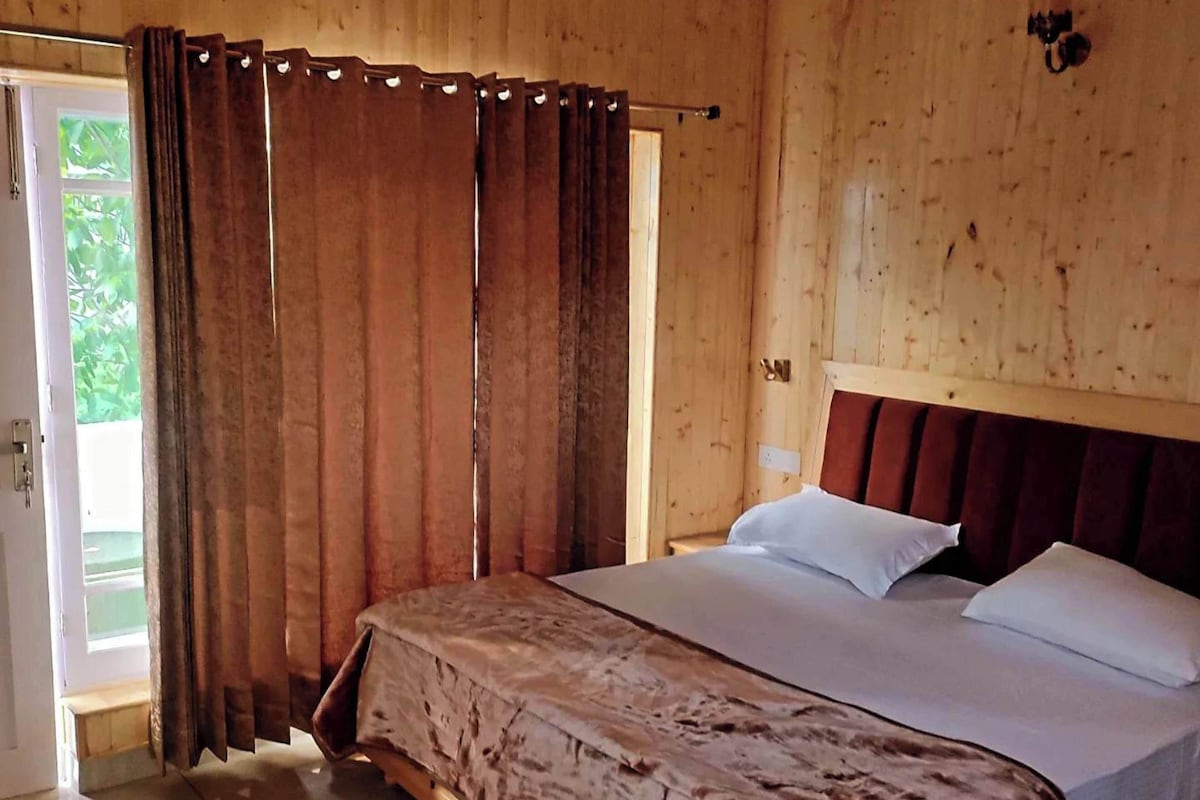 Um quarto de madeira com uma cama, cortinas e uma janela.