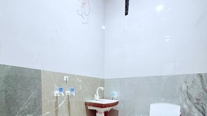 A small bathroom with a sink, toilet, and a blue bucket. - The Veteran House (Haripur)