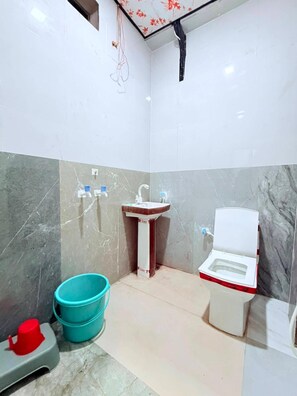 Um banheiro pequeno com pia, vaso sanitário e um balde azul.