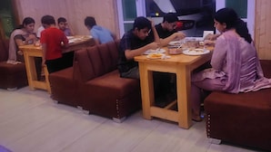 A restaurant with wooden walls and tables, people dining, and a window with a view. - The Veteran House (Haripur)