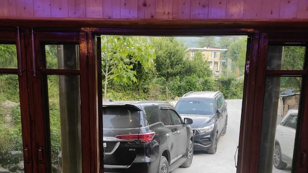 A room with a view of parked cars outside through glass doors. - The Veteran House (Haripur)