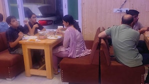 A group of people seated around a table in a room with wooden walls and a television mounted on the wall. - The Veteran House (Haripur)