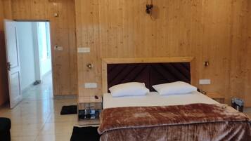 A bedroom with a wooden ceiling, a bed with a brown blanket, a ceiling fan, and a nightstand.