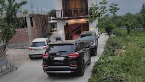 A two-story building with a balcony, parked cars, and a mountainous backdrop. - The Veteran House (Haripur)