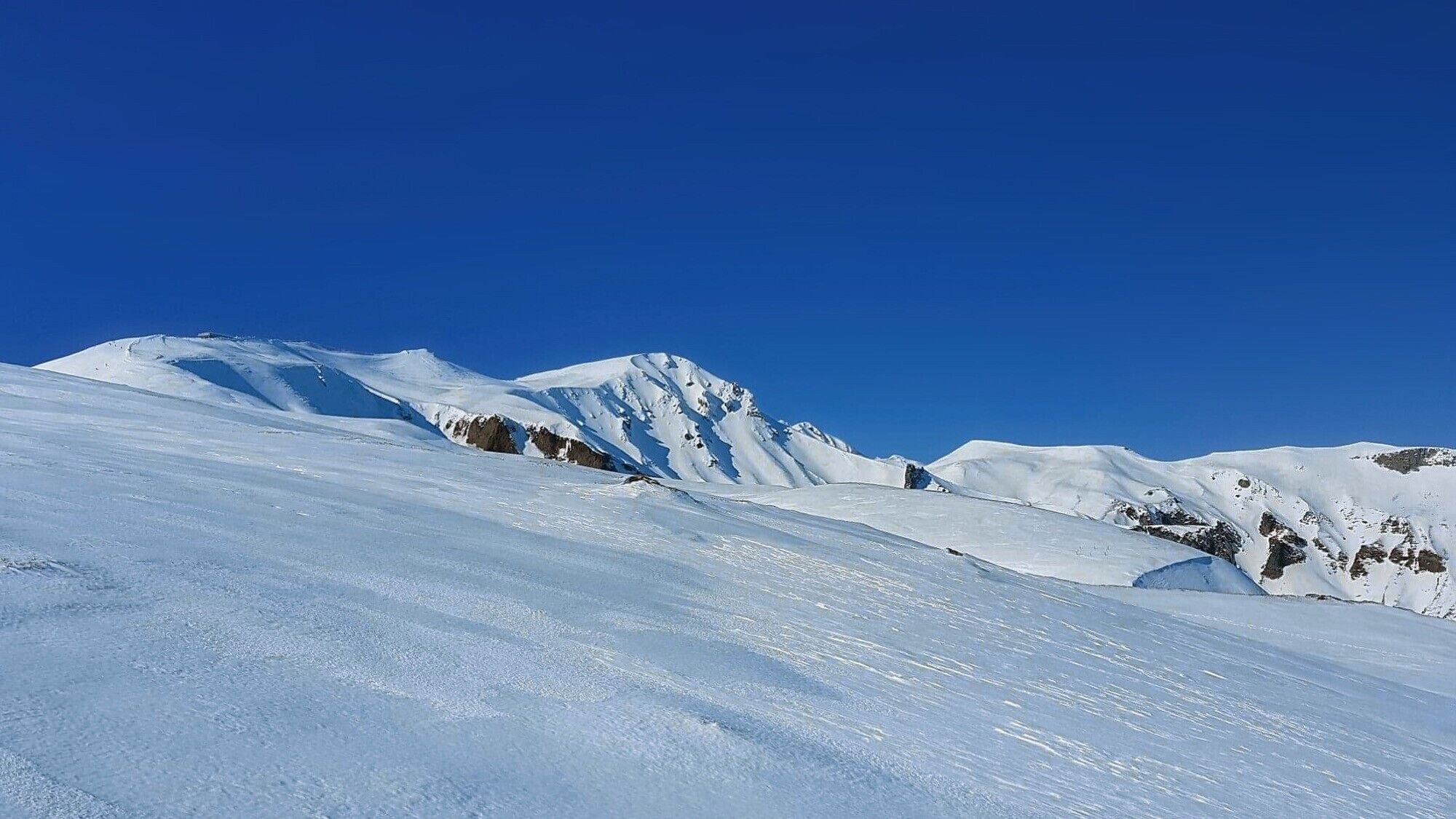 A snow-covered mountain landscape with clear blue skies.