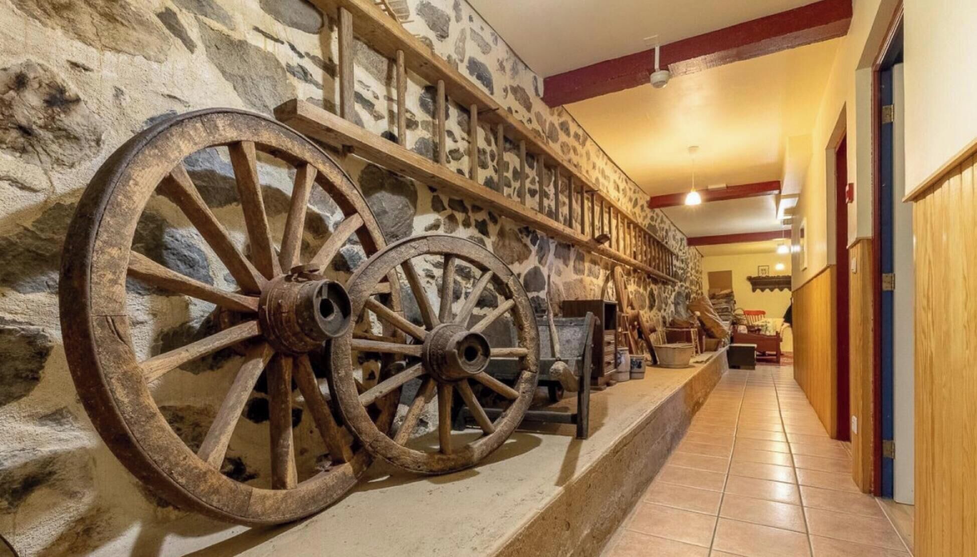 Un couloir aux murs de pierre, aux poutres en bois et aux grandes roues en bois.