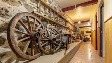 Un couloir aux murs de pierre, aux poutres en bois et aux grandes roues en bois.