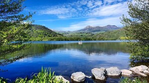 A calm lake with a boat, surrounded by lush greenery and mountains in the background. - Bed and Breakfast 'Chambre Verte' with Mountain View (Bagnols)